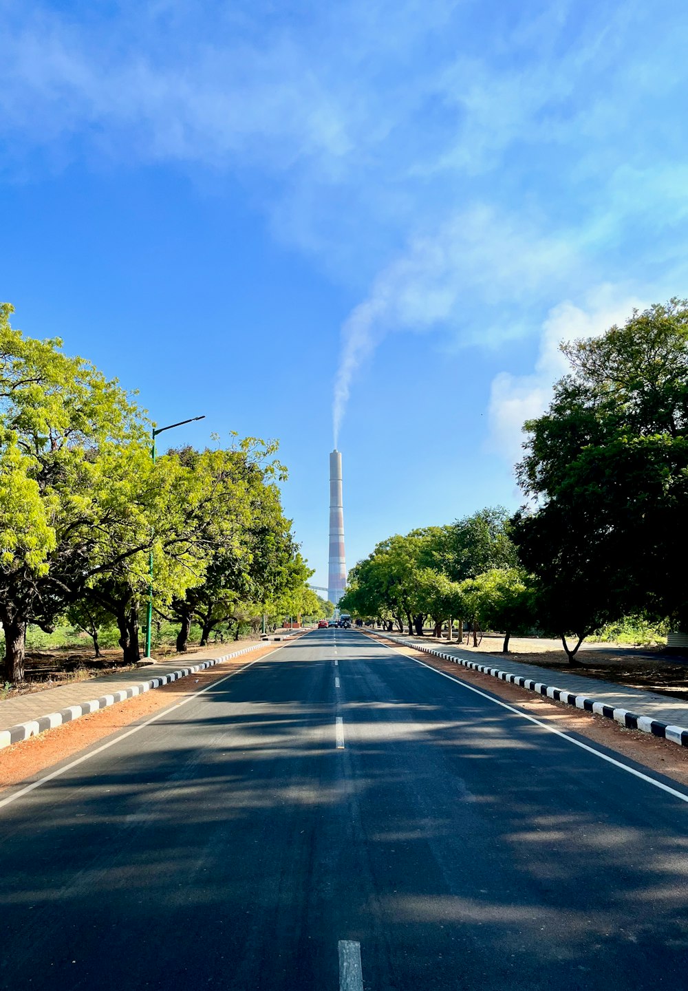 a long empty road with a tall tower in the background