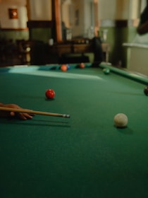 A stylish cue stick resting on the edge of a billiard table in a dimly lit, elegant room.