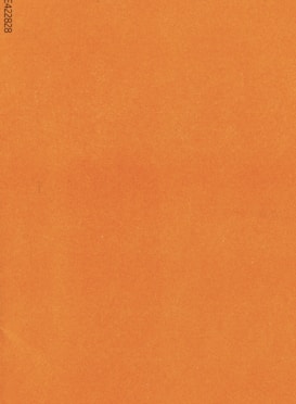 A plain, textured surface in a solid burnt orange color with a visible print of alphanumeric code in the corner.