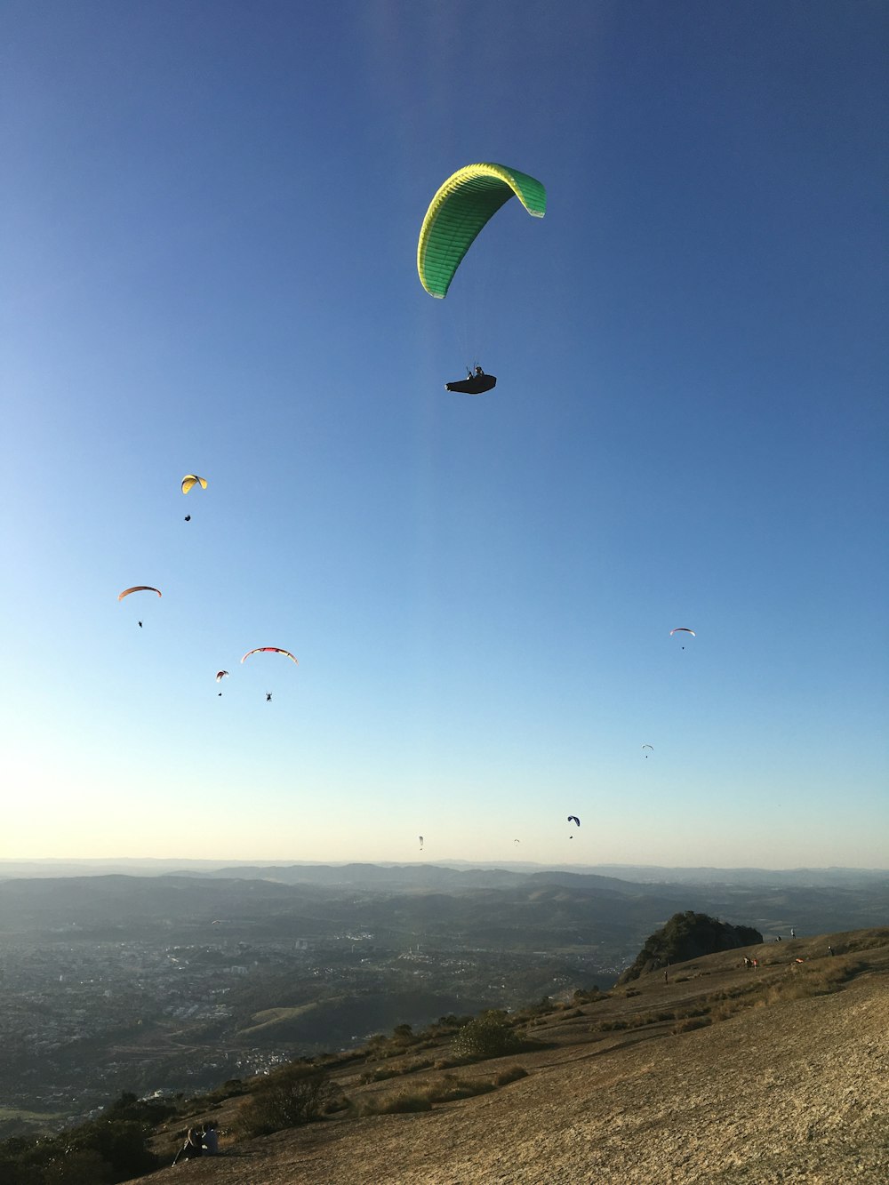 a group of people flying kites on top of a hill