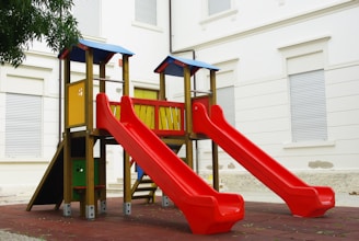 a playground with a red slide and a yellow slide