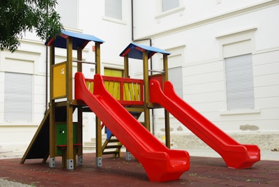 a playground with a red slide and a yellow slide