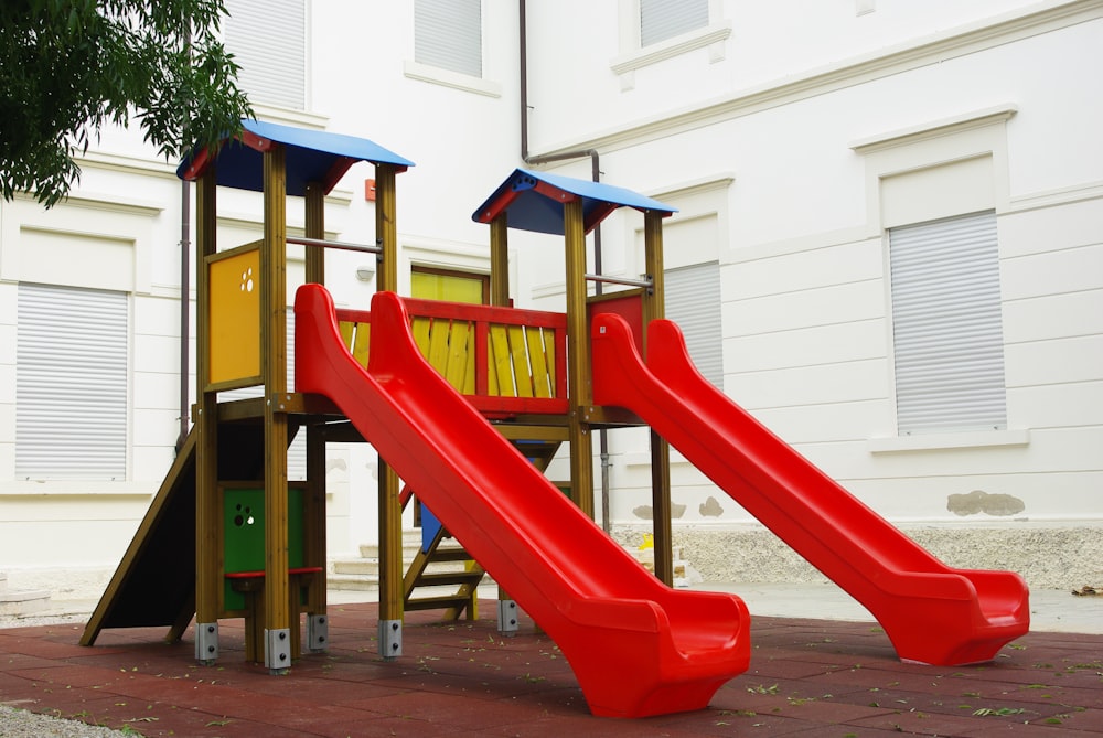 a playground with a red slide and a yellow slide