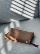 A worn leather-bound Bible resting on a wooden table with soft morning light.