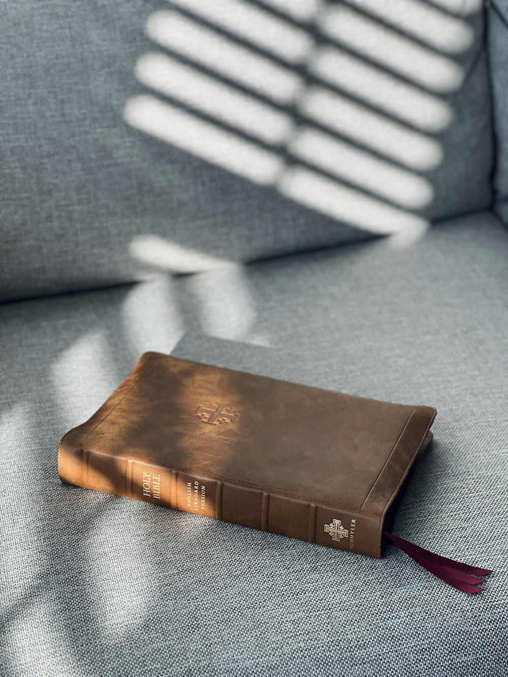 um livro marrom sentado em cima de um sofá cinza