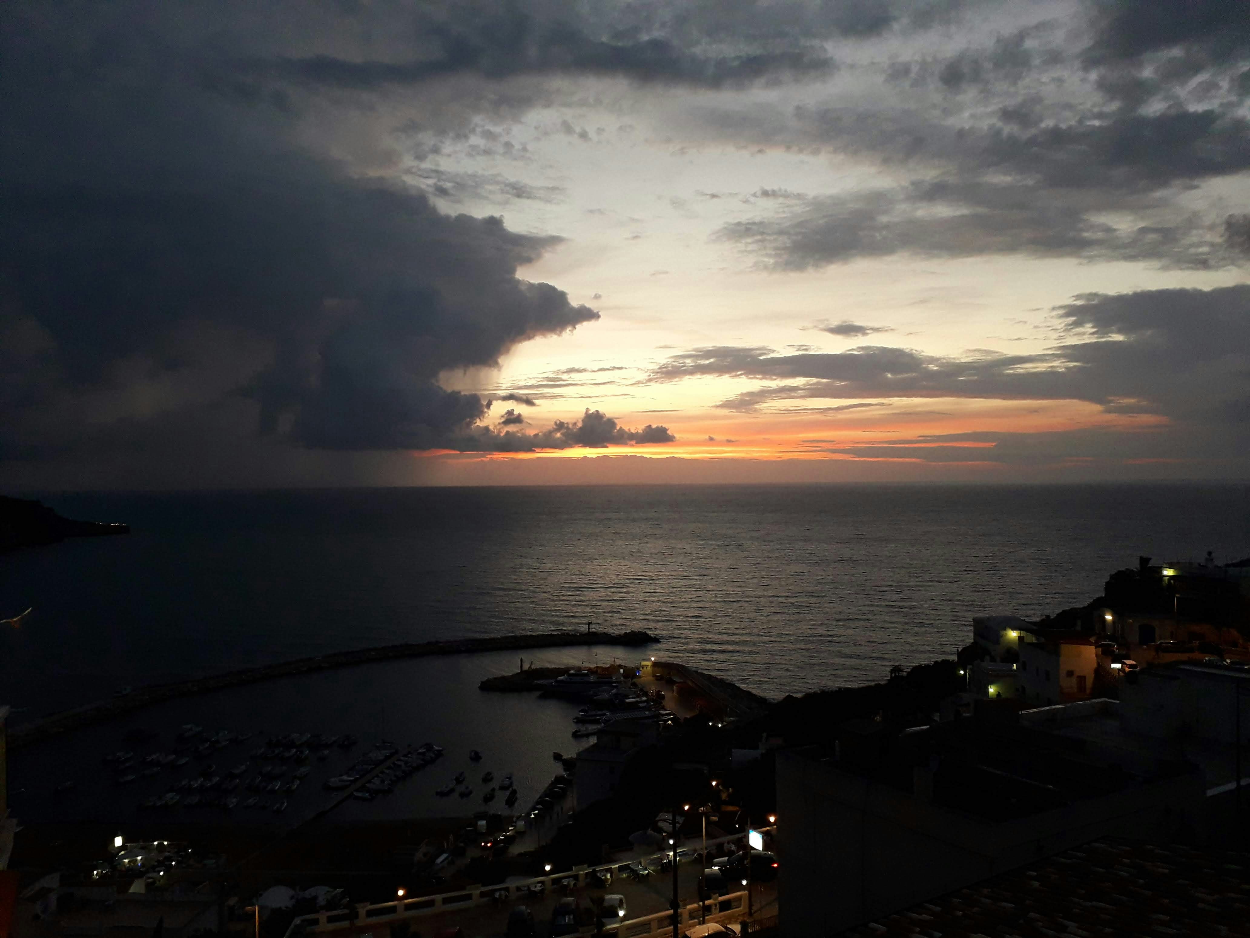 Il sole sta tramontando sull'oceano con molte nuvole