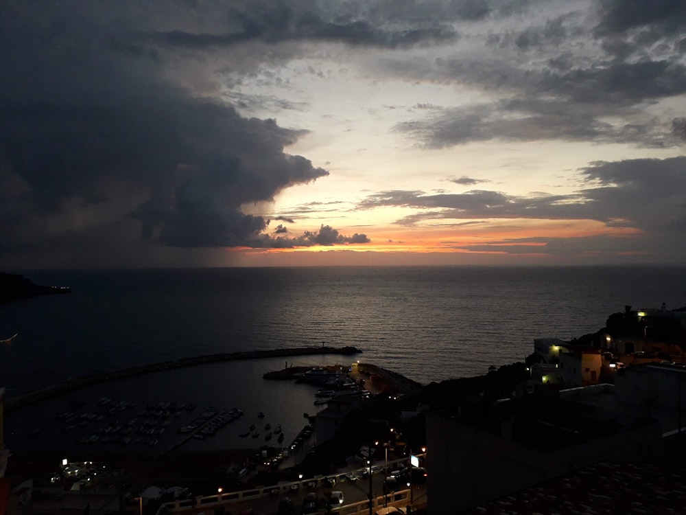 the sun is setting over the ocean with a lot of clouds