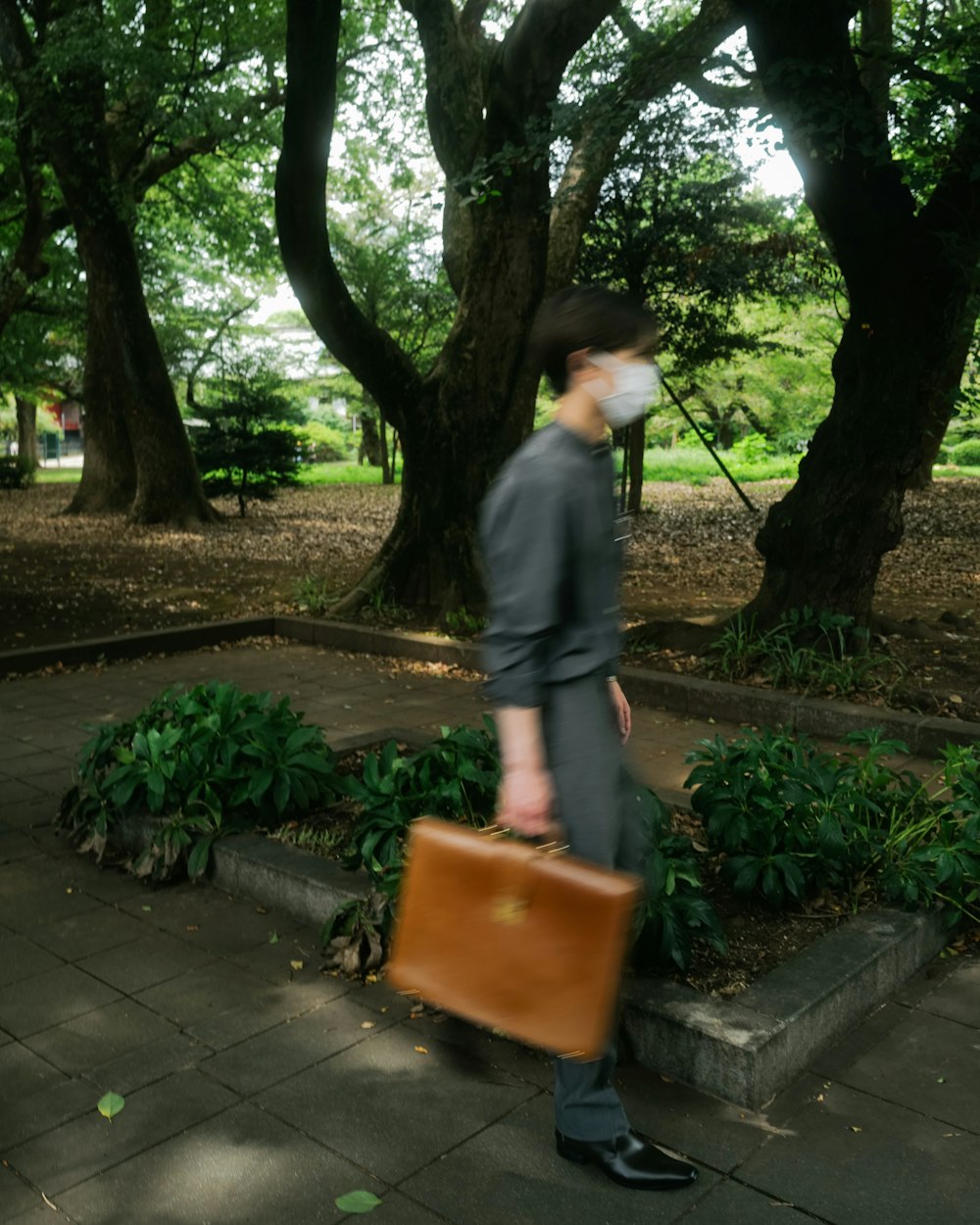 a man in a suit and hat carrying a brown suitcase