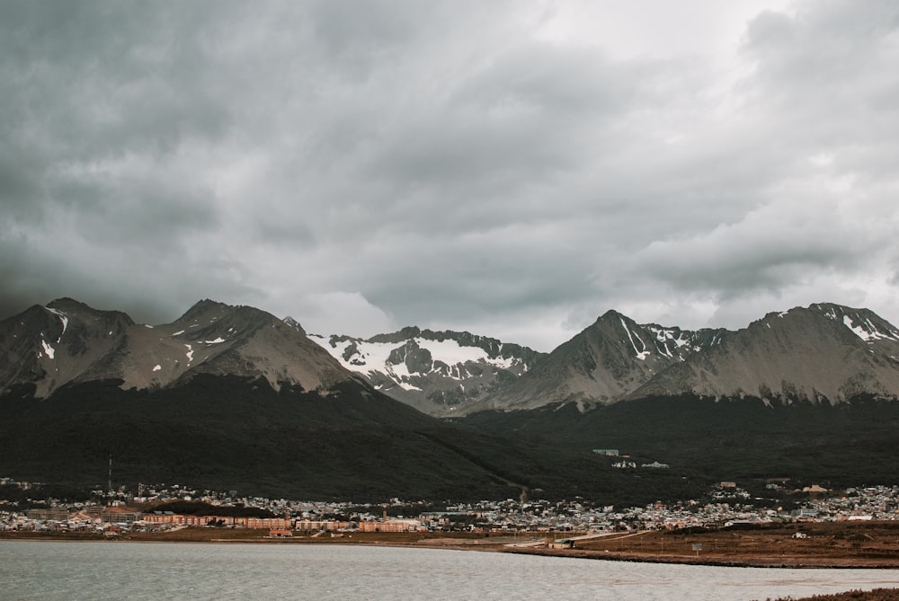 a lake surrounded by mountains under a cloudy sky