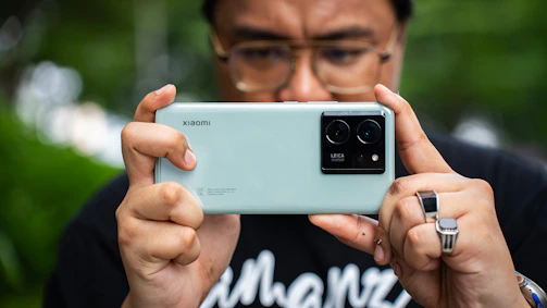Close-up of a person holding a smartphone capturing a clear iris photo with side lighting.