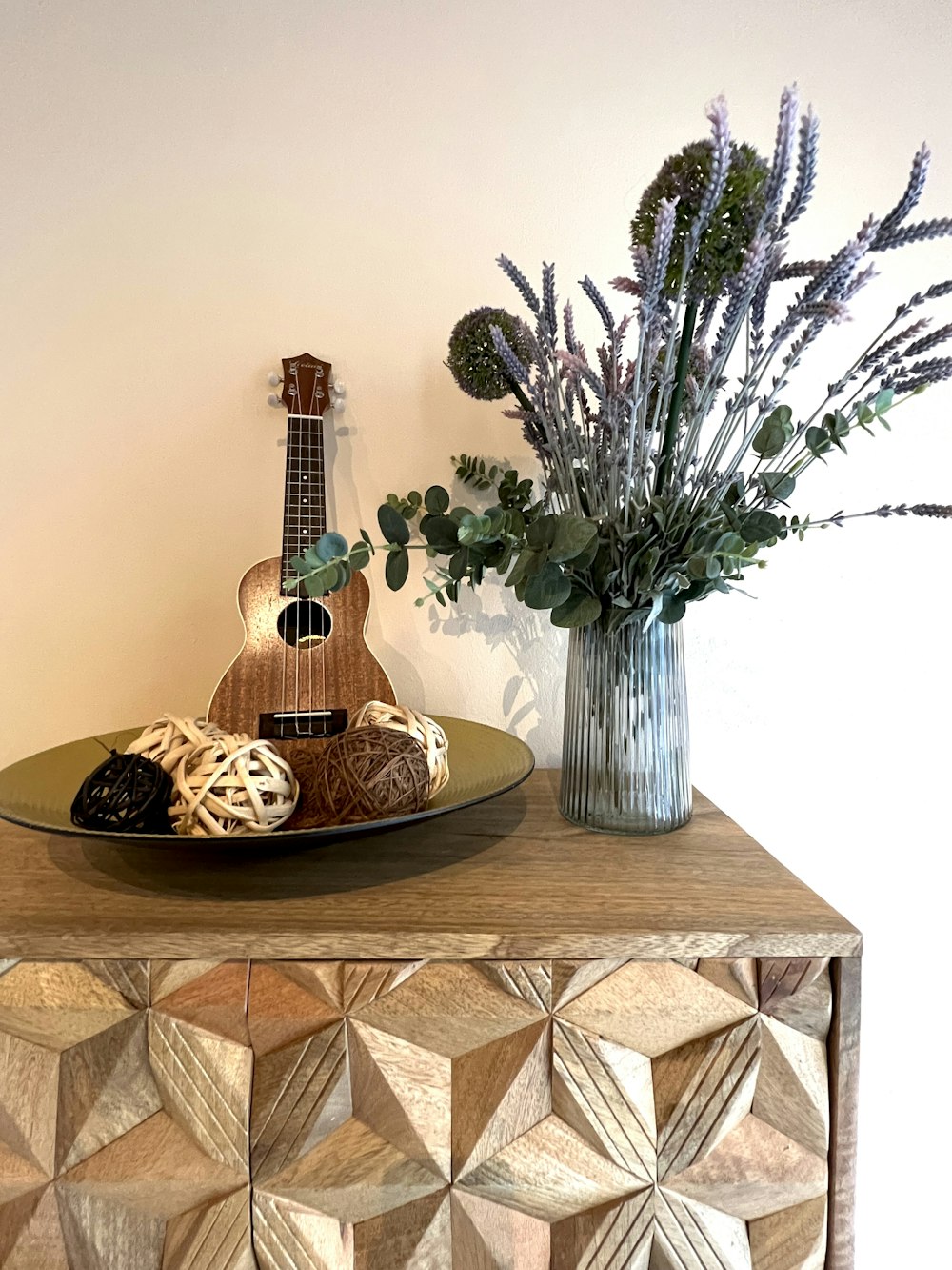 a wooden table topped with a guitar and a vase filled with flowers