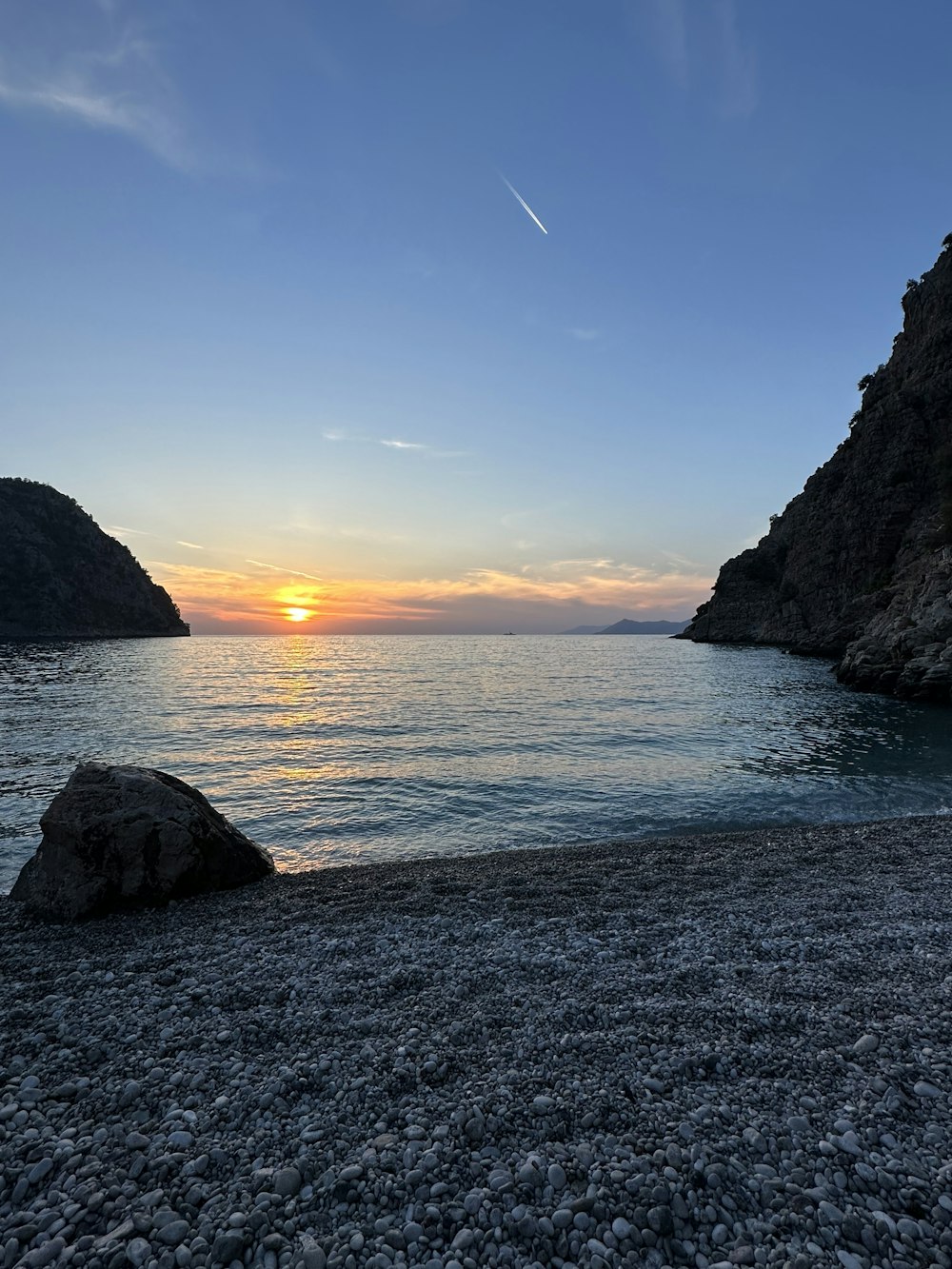 the sun is setting over a rocky beach