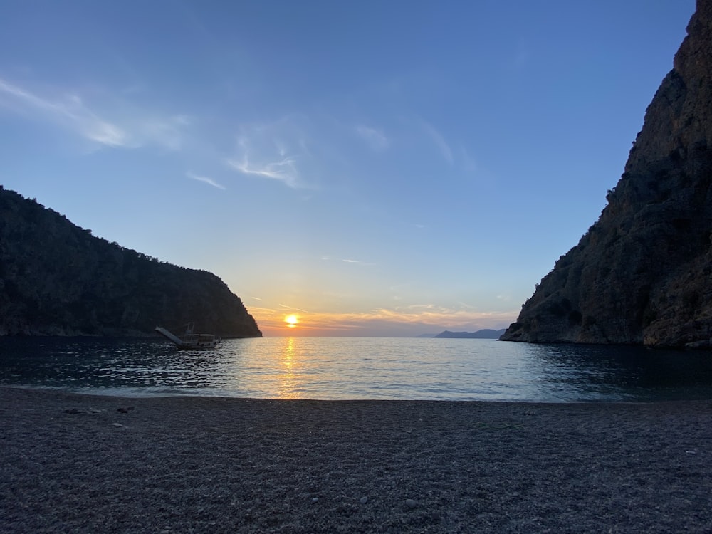 the sun is setting over the water at the beach