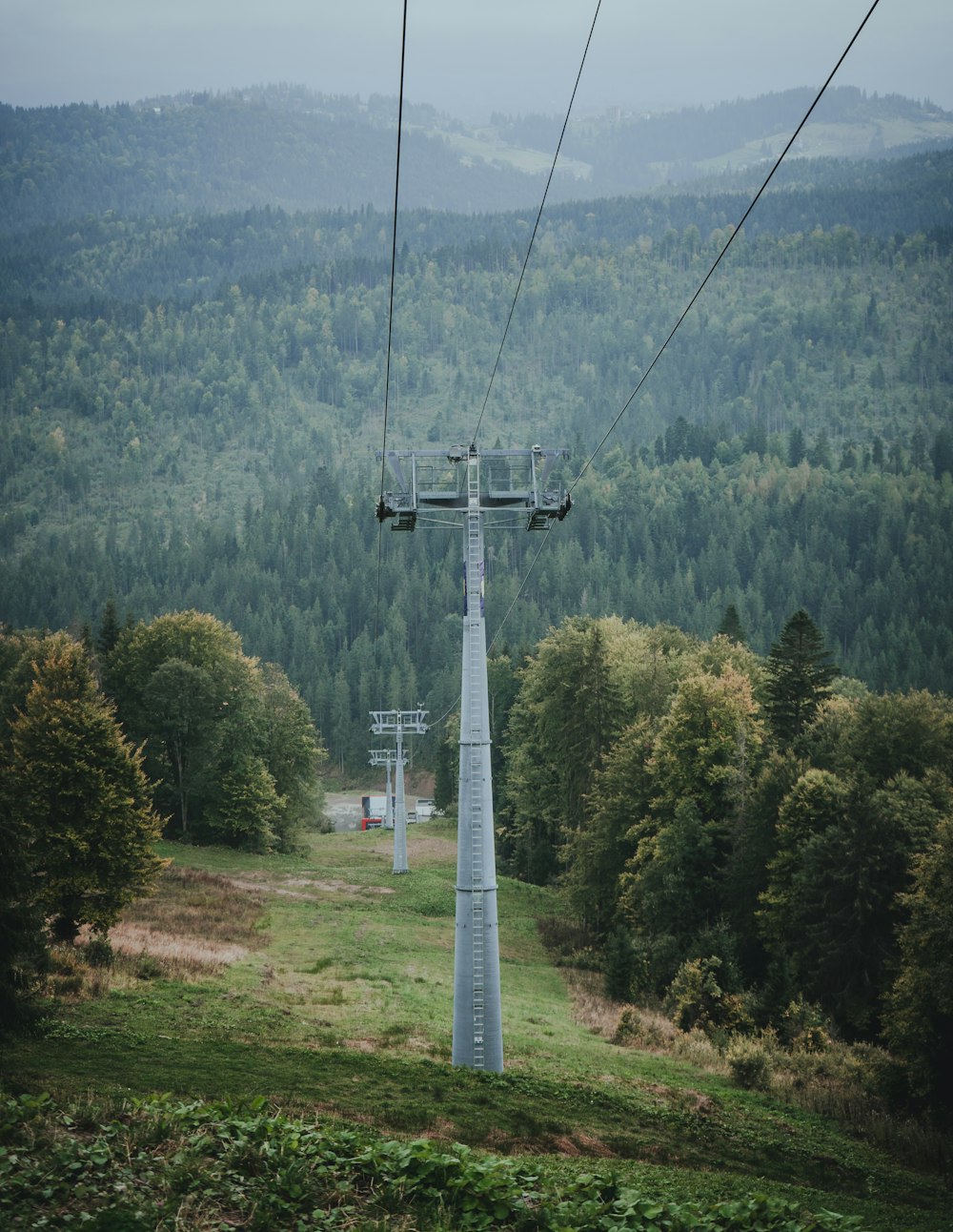 a ski lift going up a hill with trees in the background