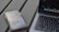 A smartphone with an app screen is placed next to a laptop with a visible keyboard and part of the screen. The phone displays various app icons and images, while the laptop shows a desktop with multiple application icons.