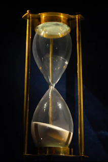 An elegant hourglass with golden sand flowing smoothly, casting soft shadows.