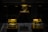Three illuminated crystal cubes rest on wooden bases, each displaying intricate celestial designs that appear to be etched or embedded within the glass. The cubes are lit with a warm, yellow glow, emphasizing the details of the celestial objects, which resemble planets or moons. The background is dark, enhancing the visibility of the glowing cubes.