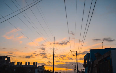 Wide shot of electrical infrastructure supporting city power grid at sunset