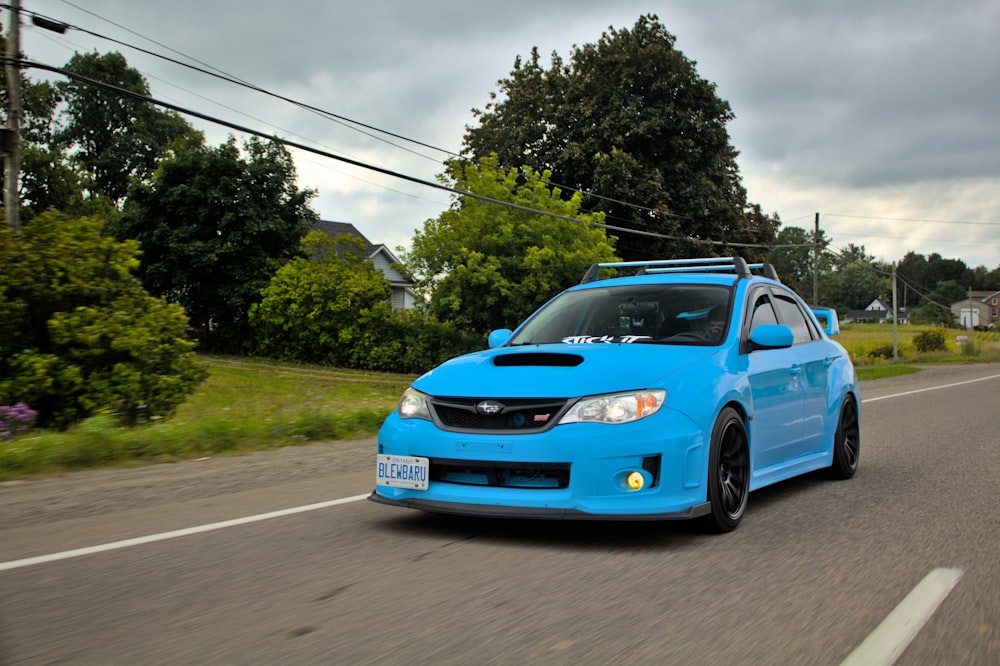 a blue car is driving down the road