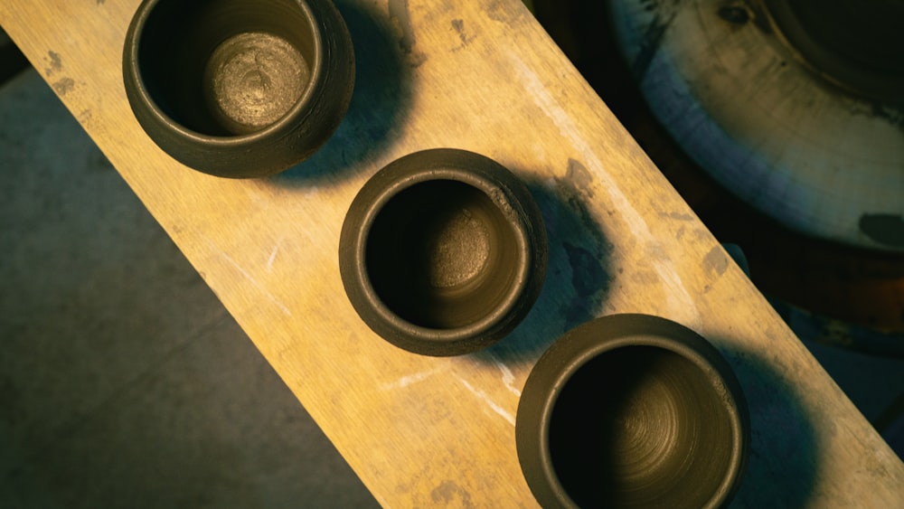 three brown bowls sitting on top of a wooden table