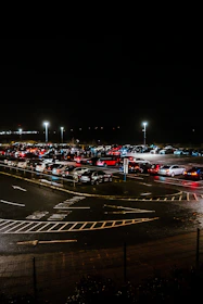 Parking attendants guiding cars efficiently at a crowded event entrance in the evening.