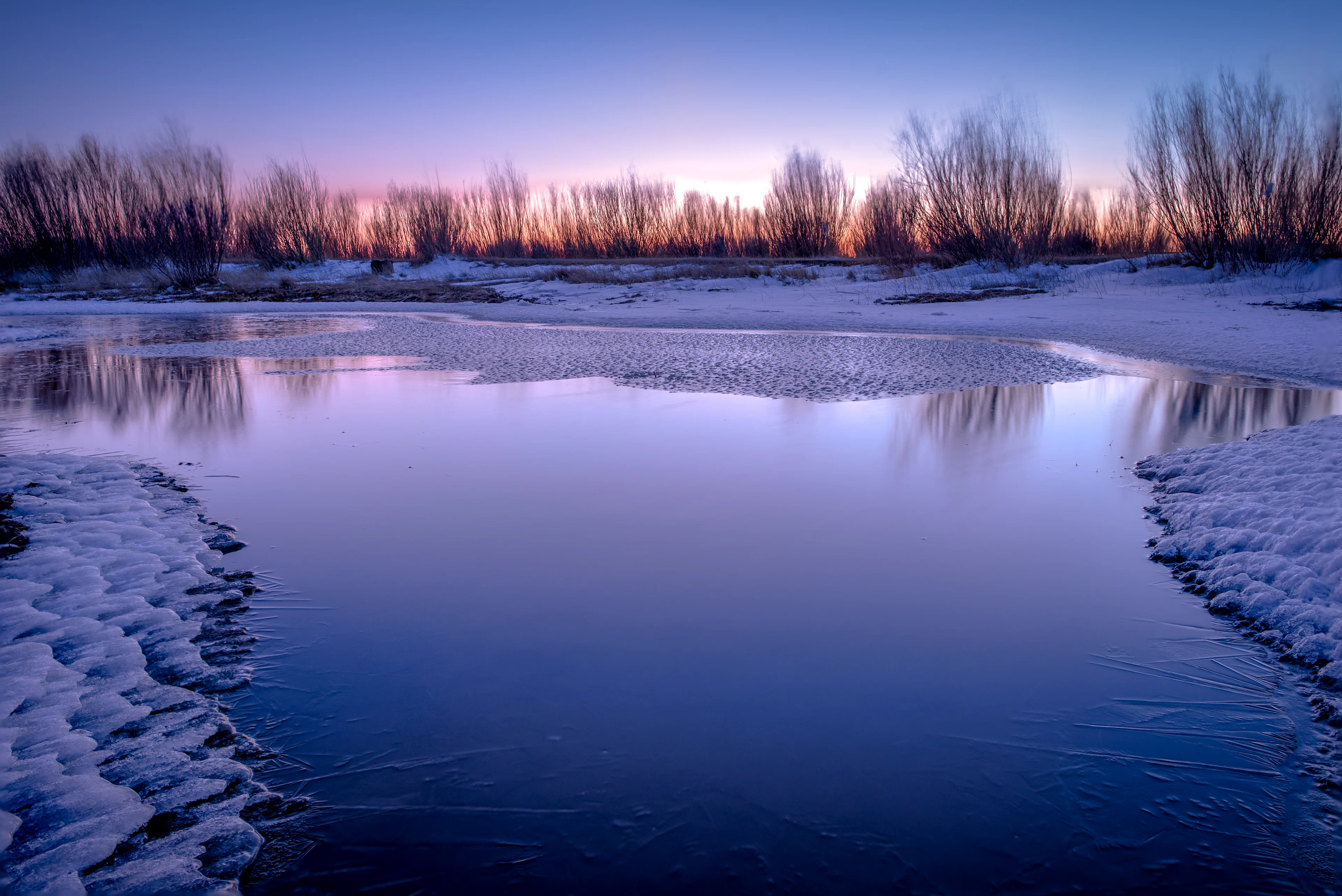 A frozen river at dawn with violet light on the ice