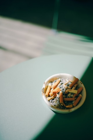 Sleek ashguard portable ashtray resting on a car dashboard with soft natural light highlighting its aluminum finish.