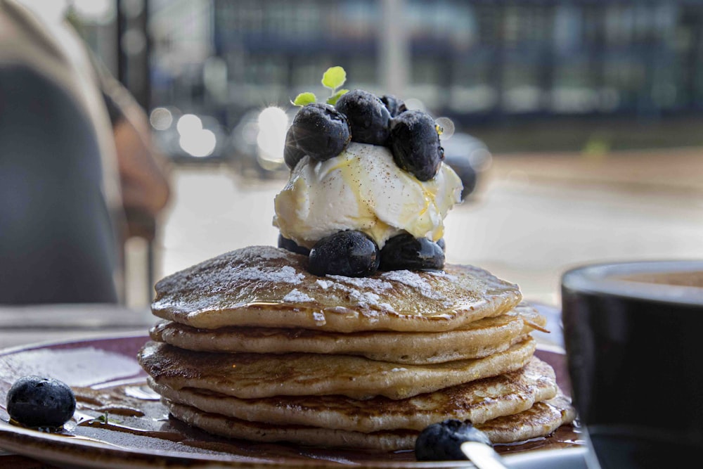 a stack of pancakes topped with ice cream and blueberries