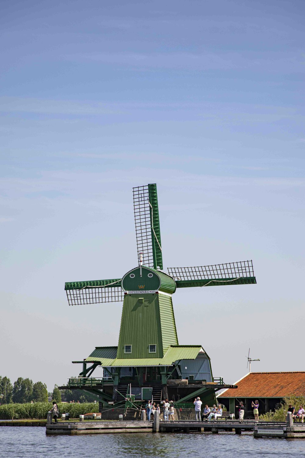 a green windmill sitting on top of a body of water
