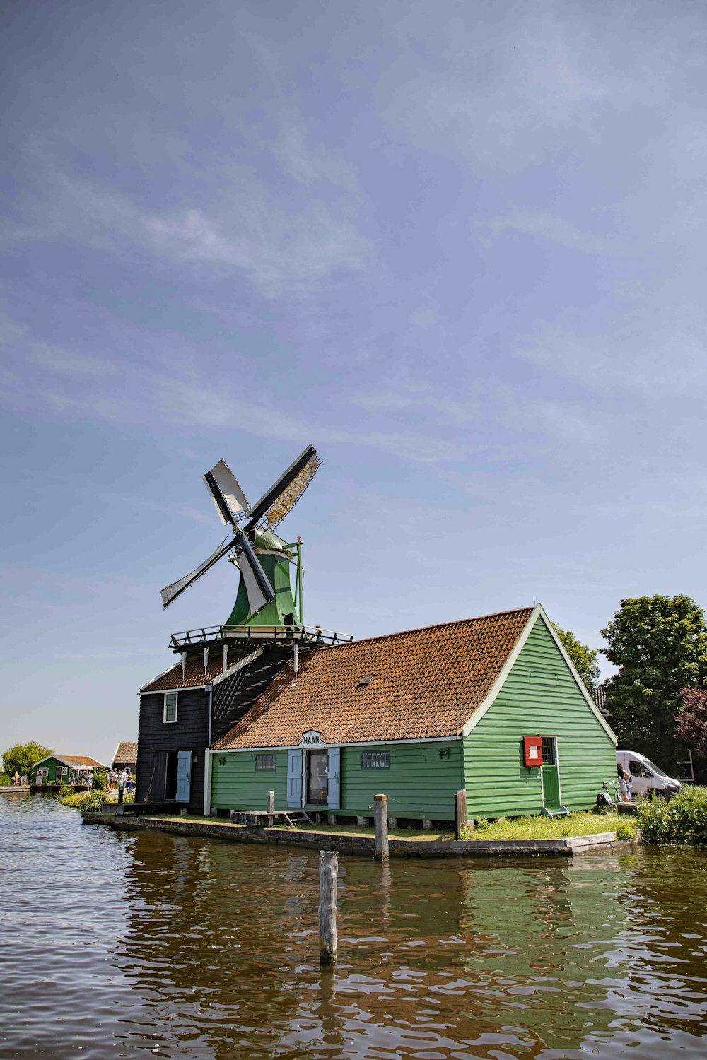 a green house with a windmill in the water