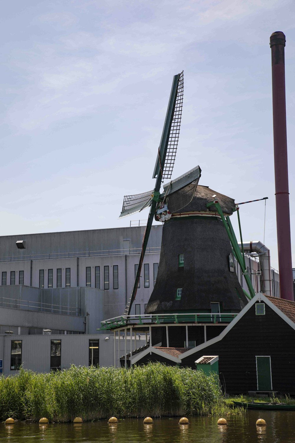 a windmill sitting on top of a river next to a building