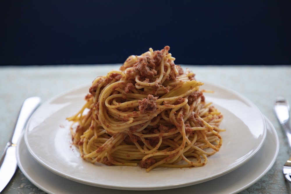 a white plate topped with spaghetti and meat