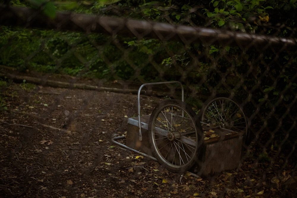 a wheelbarrow sitting on the ground behind a fence