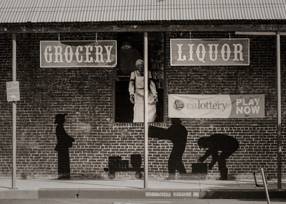 a black and white photo of a man standing in the window of a liquor store