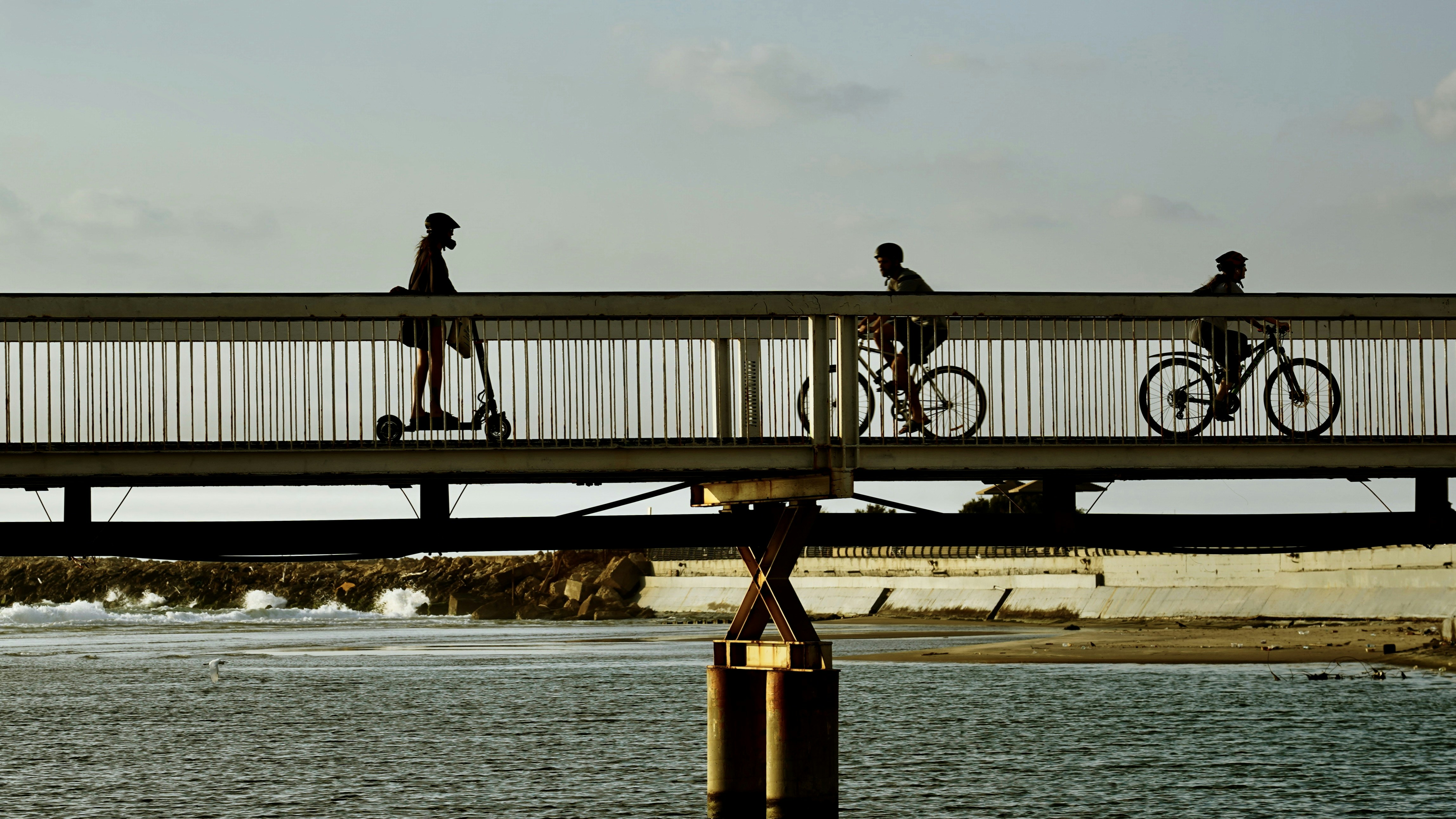 a group of people riding bikes across a bridge over a body of water