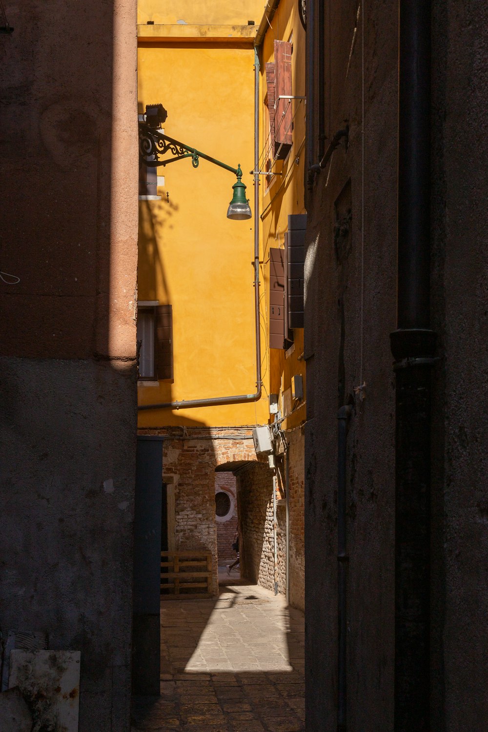 a narrow alley way with a yellow building in the background
