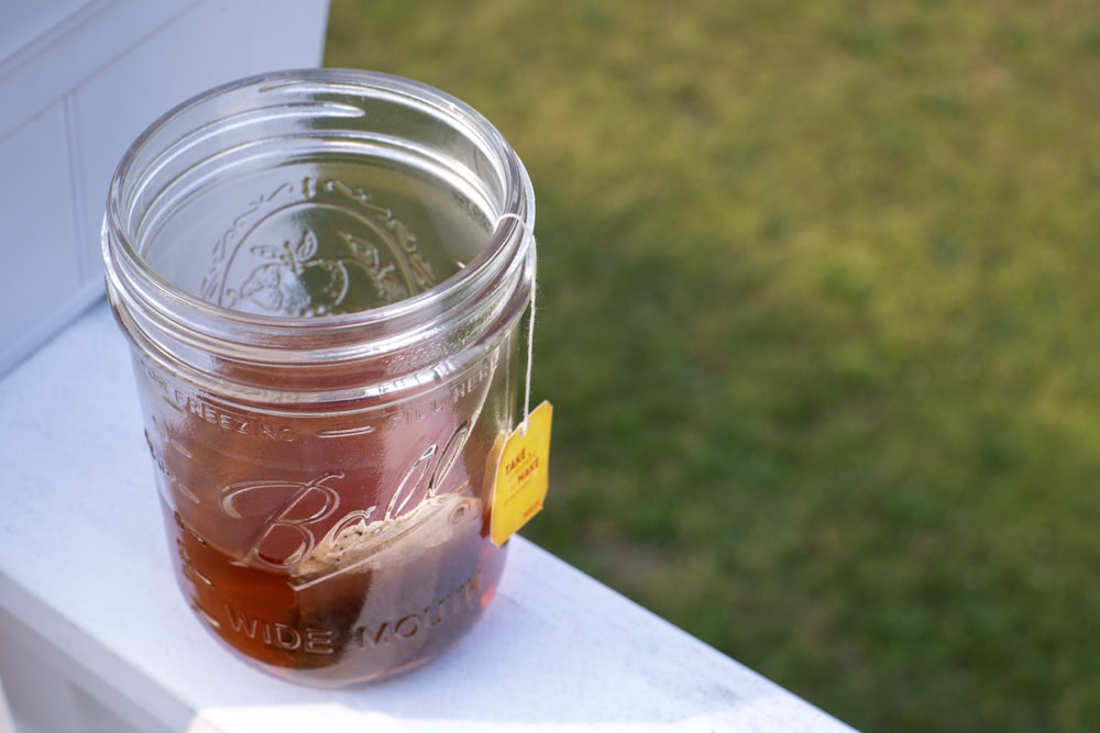 a jar of liquid sitting on top of a window sill