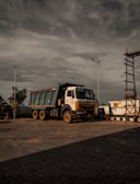 a dump truck parked in a parking lot under a cloudy sky