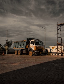 a dump truck parked in a parking lot under a cloudy sky