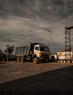 a dump truck parked in a parking lot under a cloudy sky
