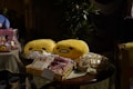 A table with various items including plush toys and packaged goods. Two yellow plushies with simple facial expressions are in clear plastic bags. Beside them, baskets hold various items, including wrapped snacks and packages featuring colorful designs. A plush toy resembling a mouse character is also visible on the left.
