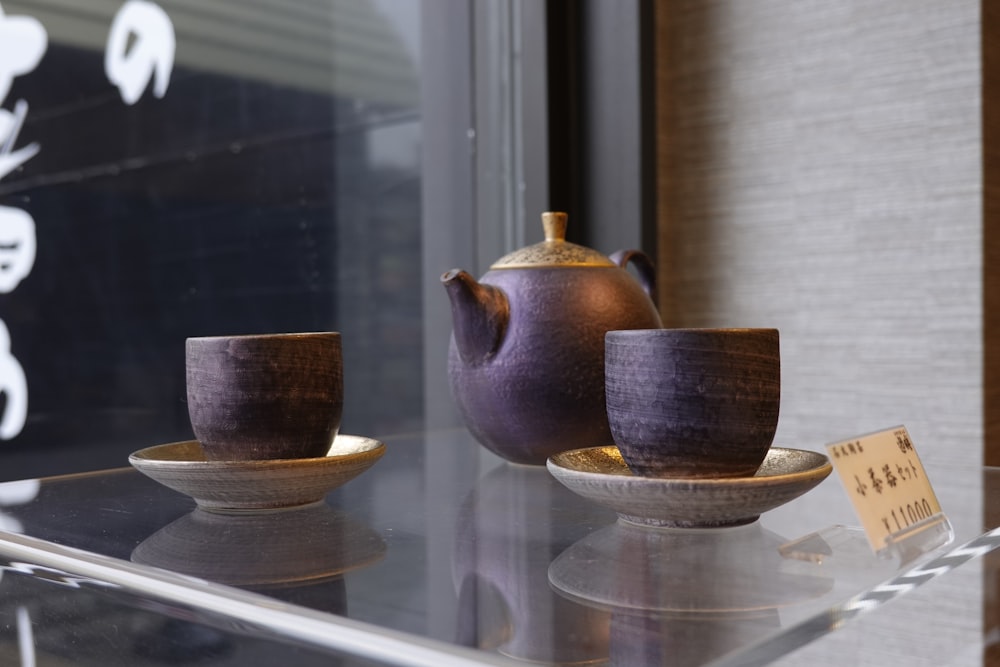 a glass shelf with a tea pot and two cups on it