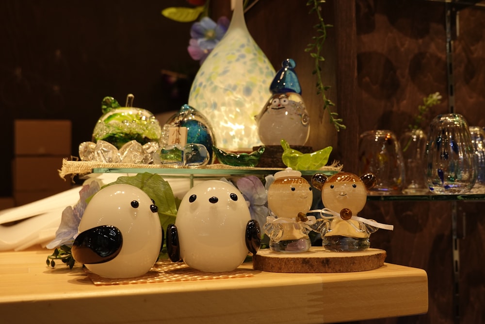 a table topped with lots of glass figurines on top of a wooden table