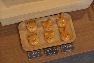 A colorful assortment of freshly baked cute animal-shaped bread on a wooden tray.