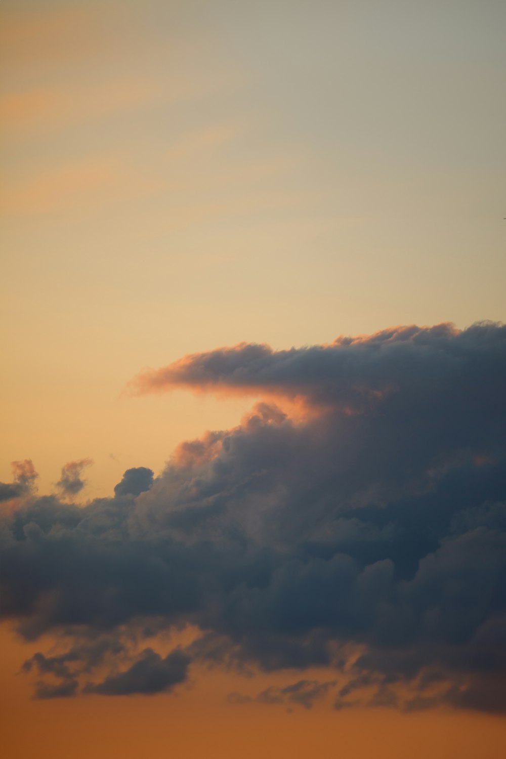 a plane flying through a cloudy sky at sunset