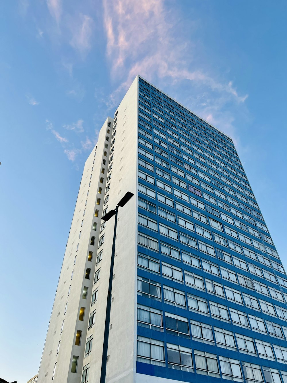 Un alto edificio blanco y azul junto a una farola