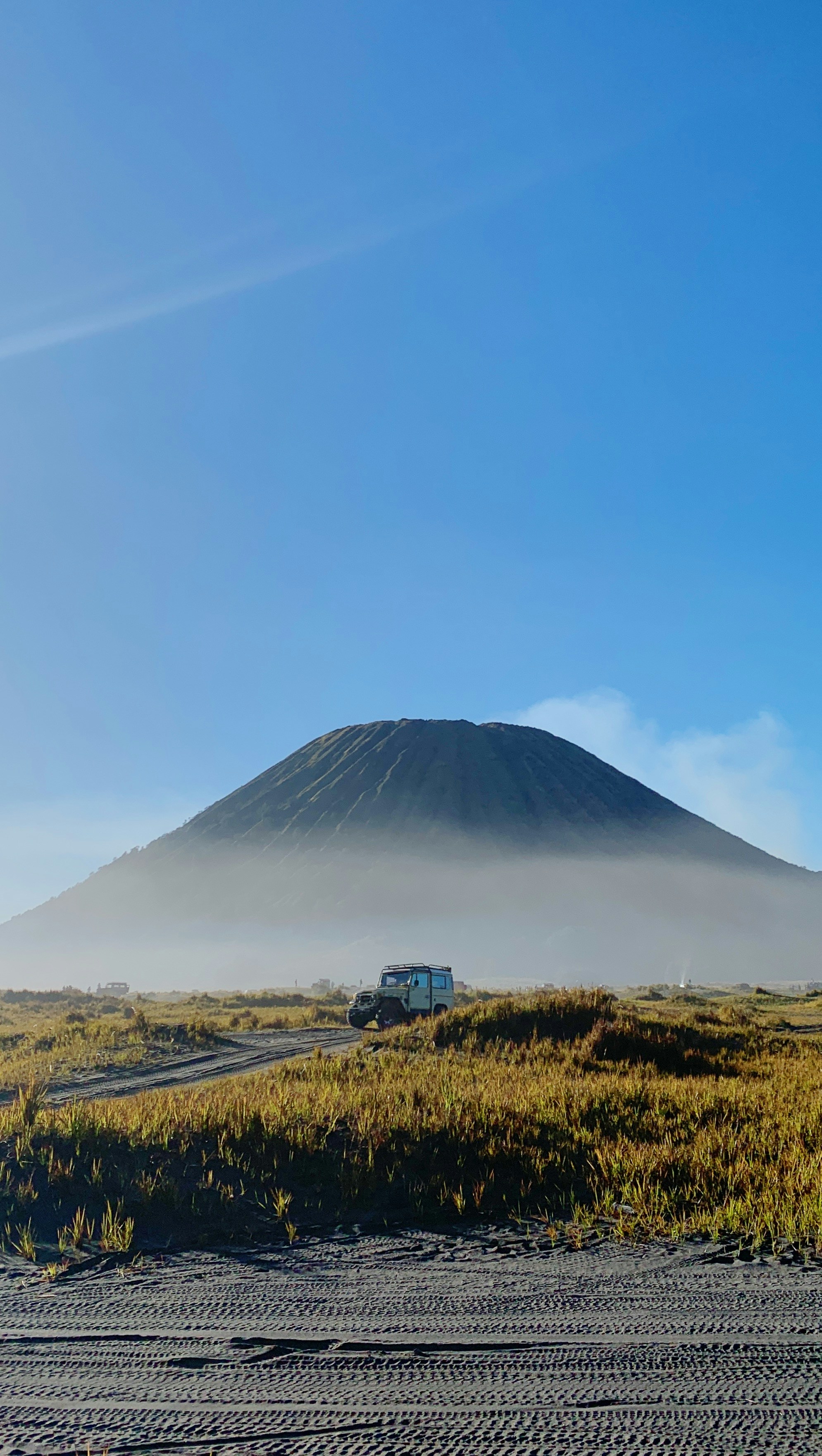 a truck driving down a dirt road near a mountain