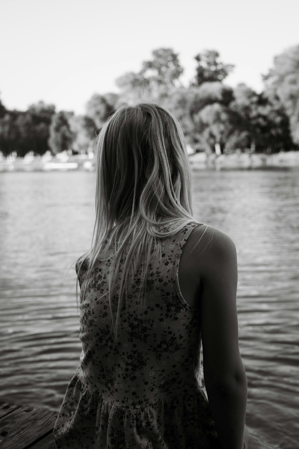 a woman sitting on a dock looking at the water