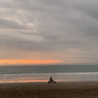 A rider cruising along Puri’s beach road on a stylish motorcycle at sunset.