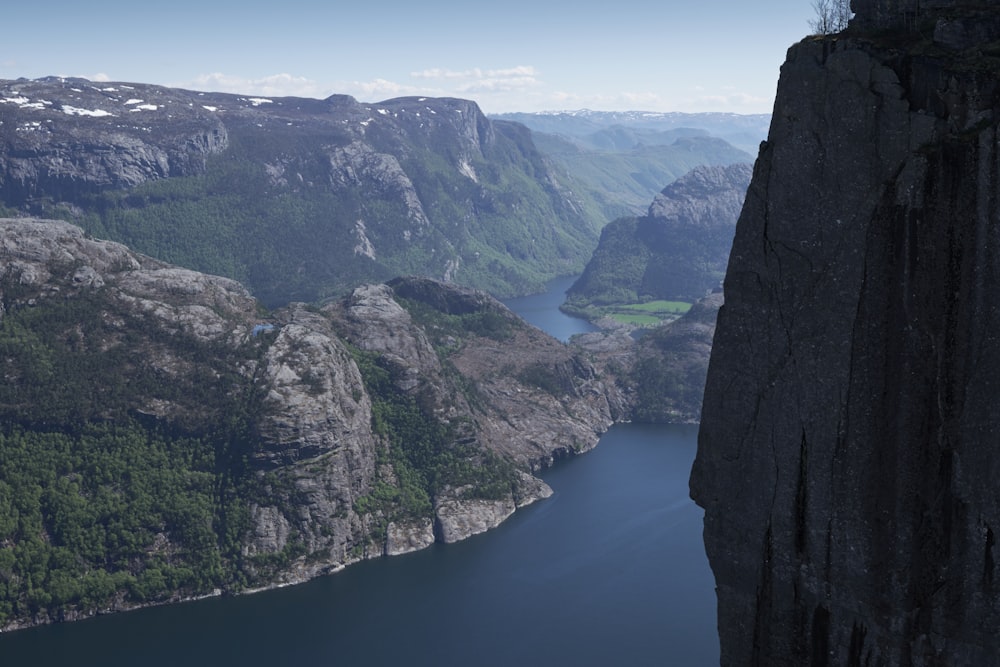 a man standing on top of a cliff next to a lake